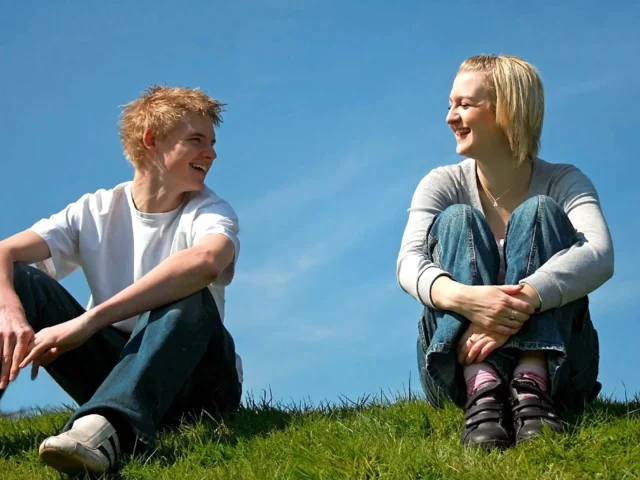 Άνδρας και γυναίκα κάθονται στο γρασίδι και συζητούν, συμβολίζοντας τη φιλία ανάμεσα στα δύο φύλα