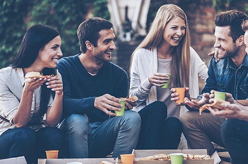 Άνδρες και γυναίκες γελούν μαζί σε παρέα, δείχνοντας φυσική διαφυλική φιλία