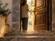 Γυναίκα από πίσω στο κατώφλι μιας ανοιχτής ξύλινης πόρτας σε πέτρινη σκάλα, με το φως του ήλιου να μπαίνει από έξω
