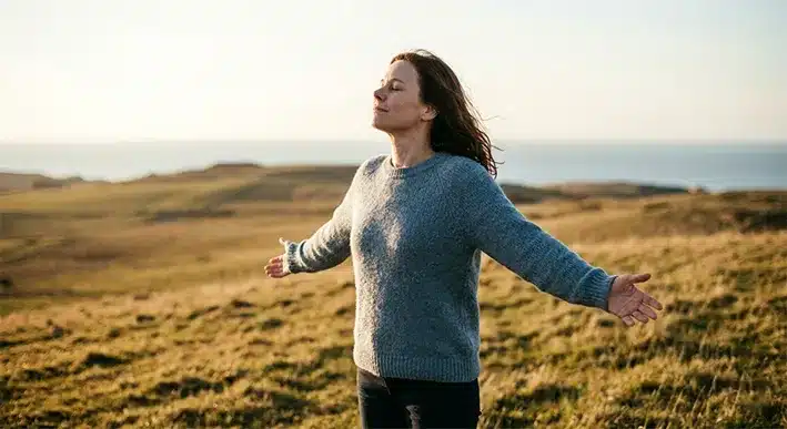 Ενήλικας στέκεται με ανοιχτά χέρια σε ανοιχτό τοπίο κατά τη χρυσή ώρα, συμβολίζοντας την απελευθέρωση από τους οικογενειακούς ρόλους.