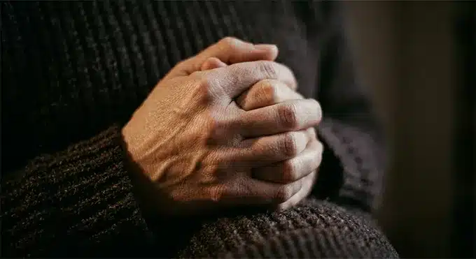 Κοντινή λήψη σφιγμένων χεριών ενήλικα, που αποδίδει την εσωτερική ένταση και τη σωματική μνήμη των παλιών οικογενειακών ρόλων